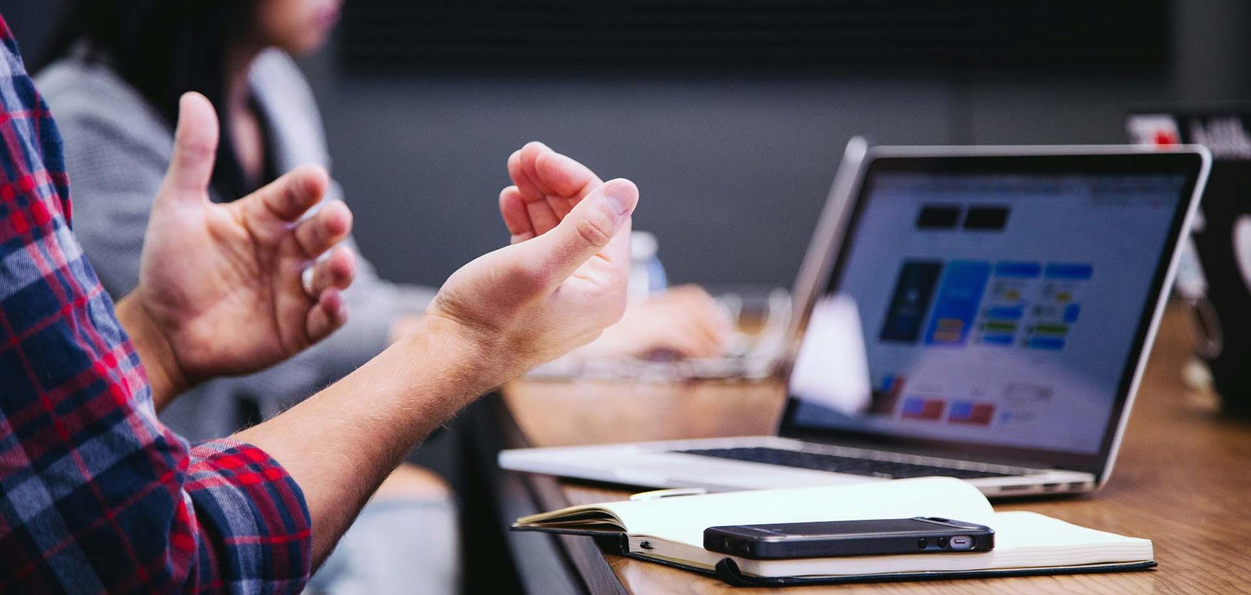 A pair of hands gesticulating in front of a laptop screen